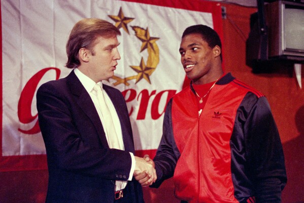 Donald Trump estrecha la mano de Herschel Walker en Nueva York después de llegar a un acuerdo sobre un contrato de cuatro años con el equipo de fútbol americano New Jersey Generals USFL, el 8 de marzo de 1984. (Foto AP/Dave Pickoff, Archivo)